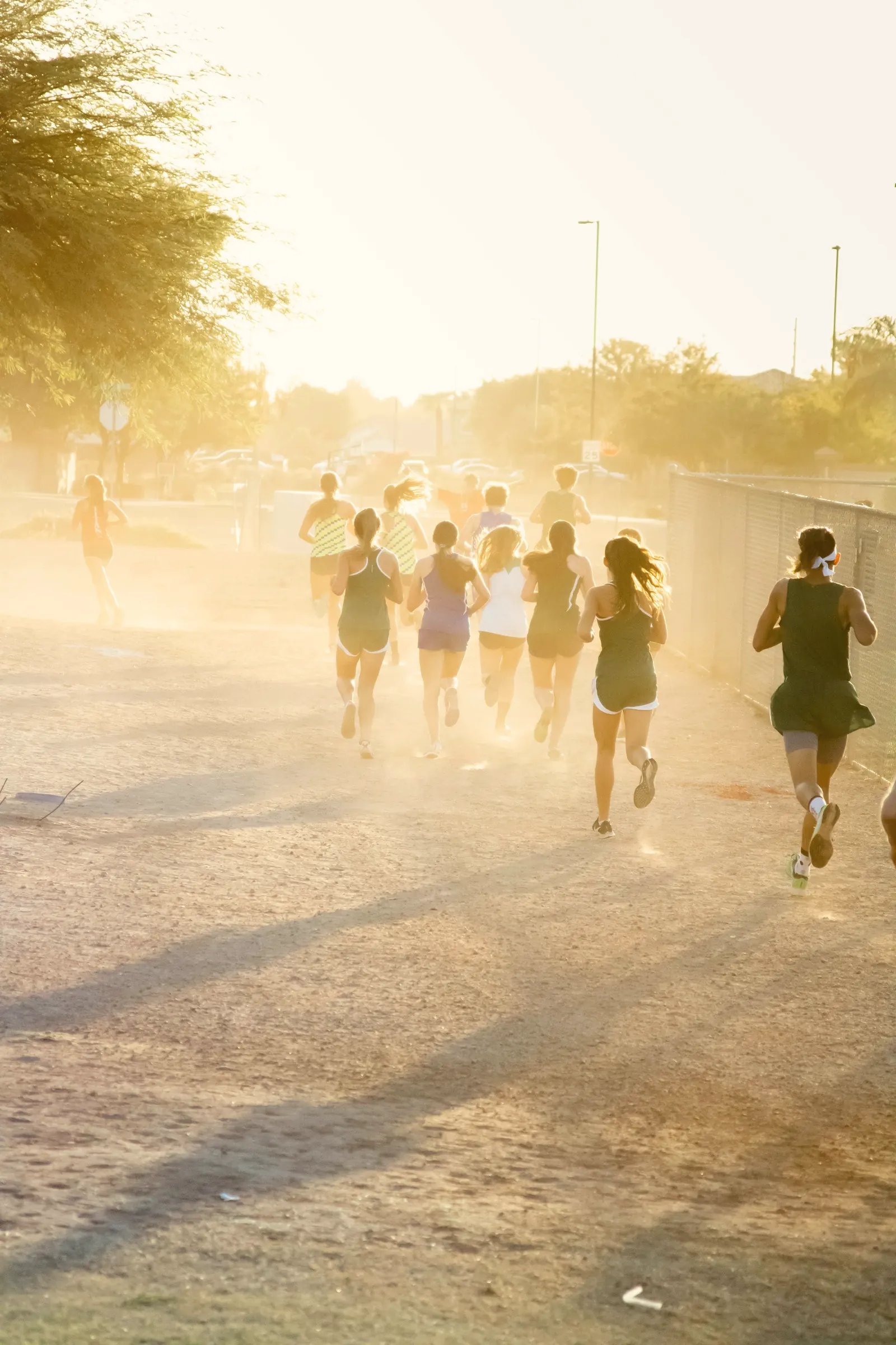 A run club pack heading down a dusty road into hazy golden morning sun